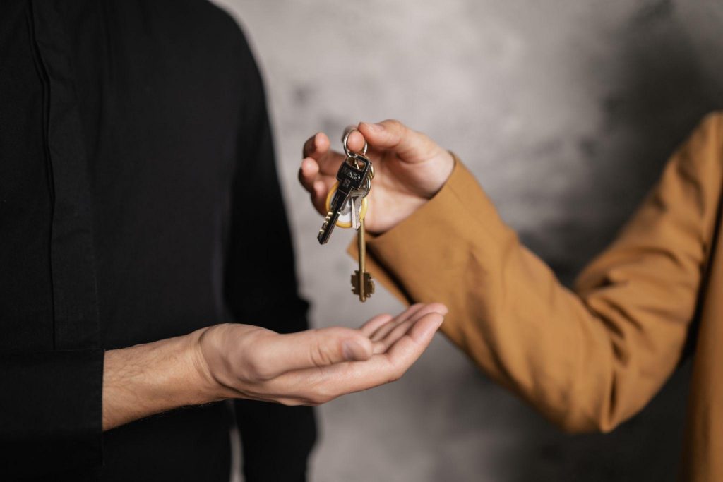 Closeup of real estate agents hand giving house key to client